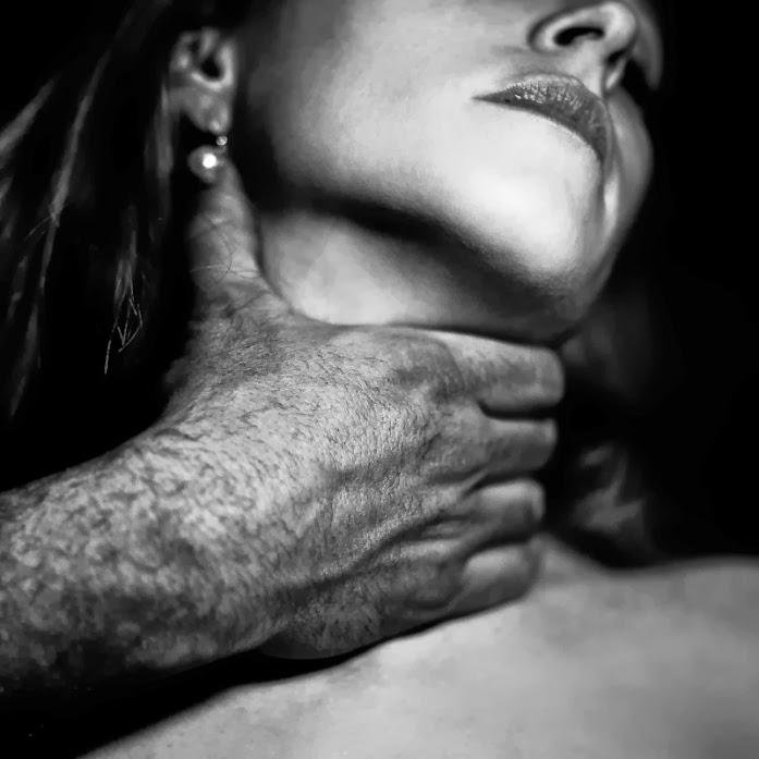 Fotografía en blanco y negro una mano de un hombre sobre el cuello de una mujer