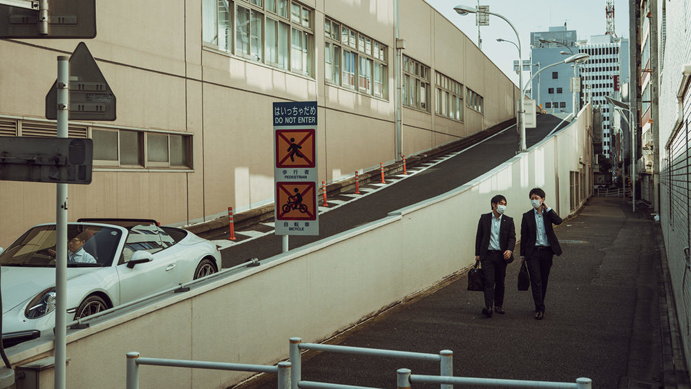 Un par de personas con mascarilla andando en las calles de Tokio