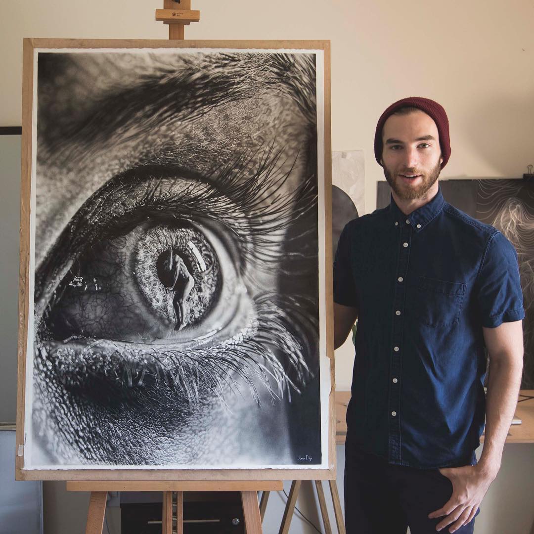 El artista Jono Drya junto a uno de sus dibujos a lápiz