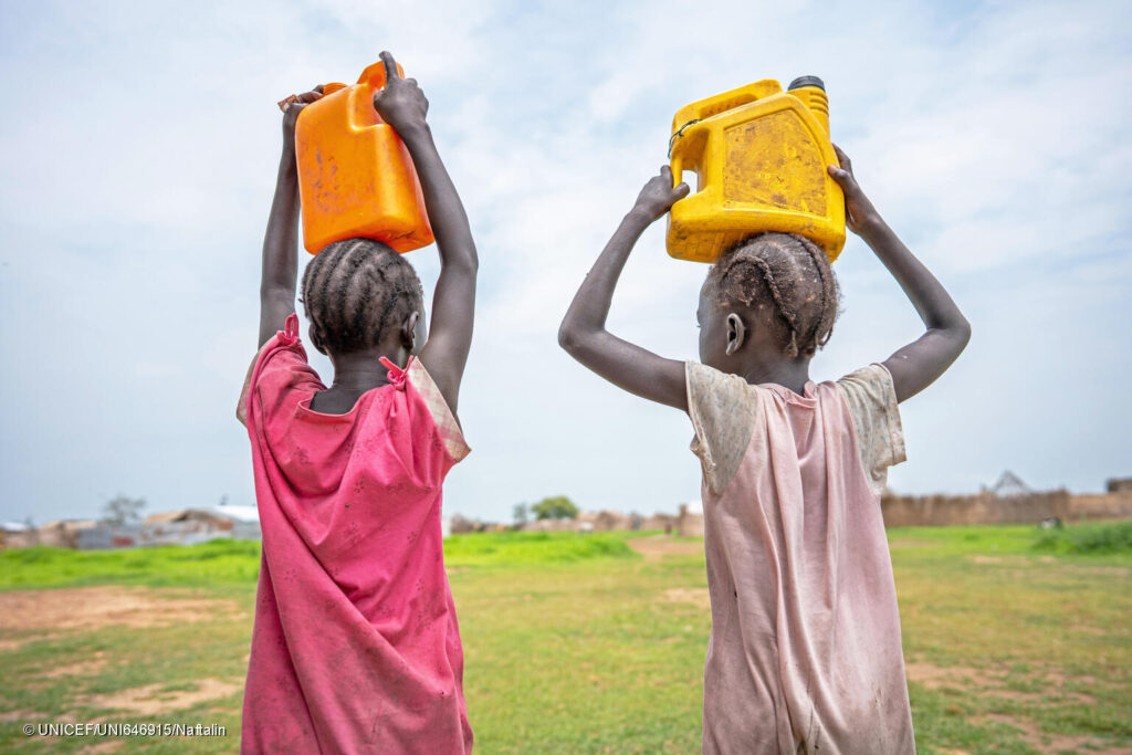 Unas niñas llevan agua a casa en la ciudad de Renk, en Sudán del Sur.
