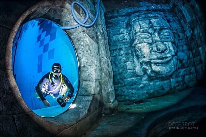 un buzo accede a una cueva con esculturas de estilo camboyano