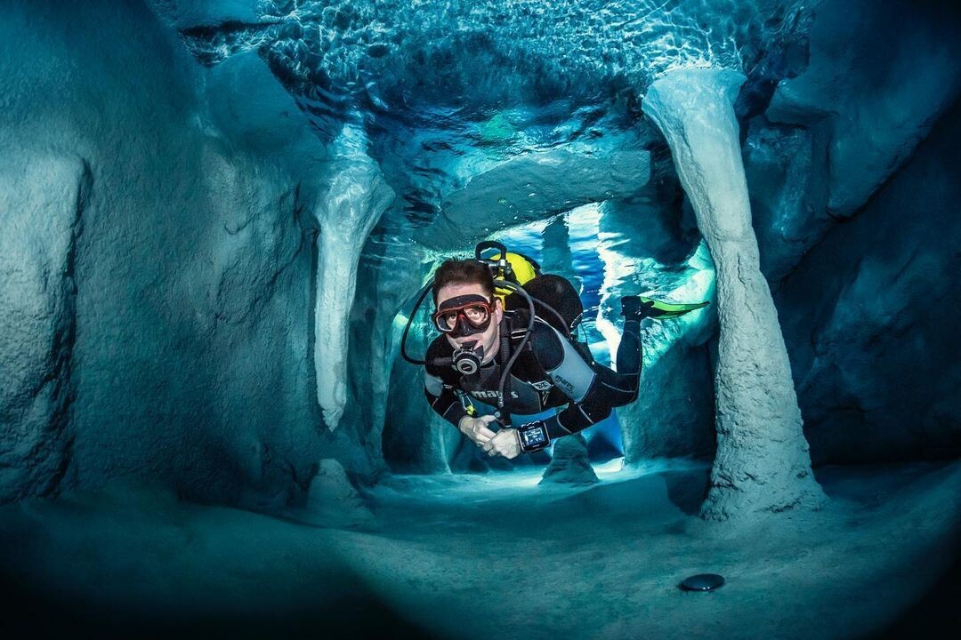 un buzo transitando el escenario de una cueva submarina artificial