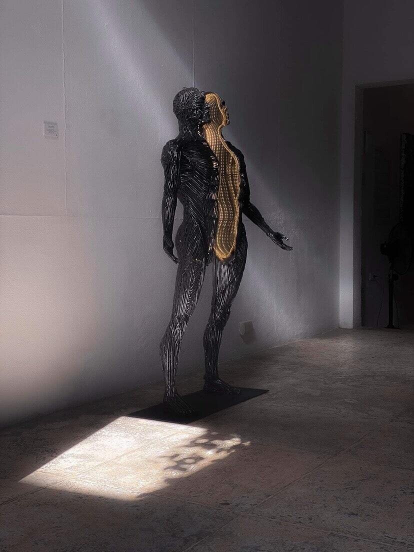 escultura metálica con luz en su interior que representa a una figura humana y es de tamaño real