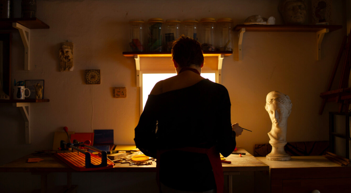 Una persona trabaja de espaldas a una ventana en lo que parece ser su taller