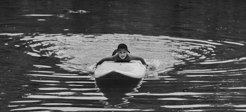 Niño sobre tabla surf en un lago