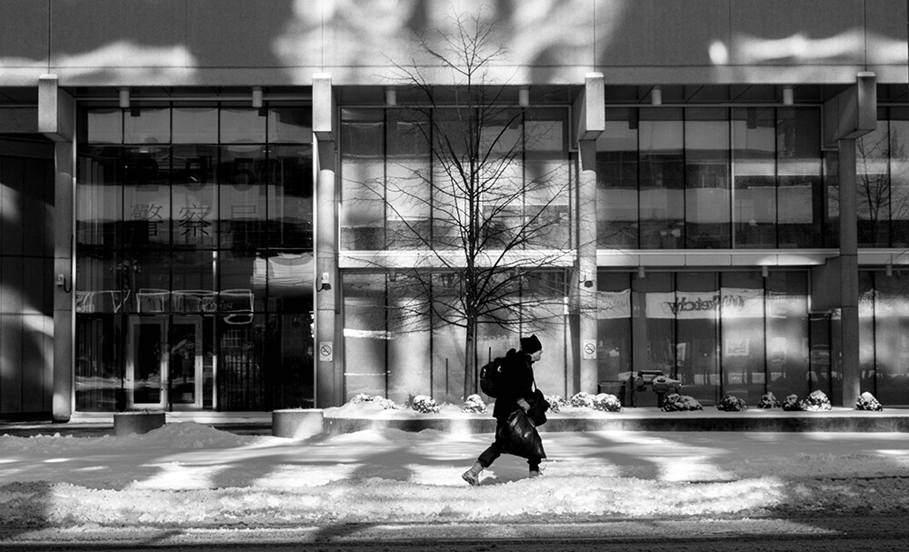 Persona paseando entre edificios con nieve