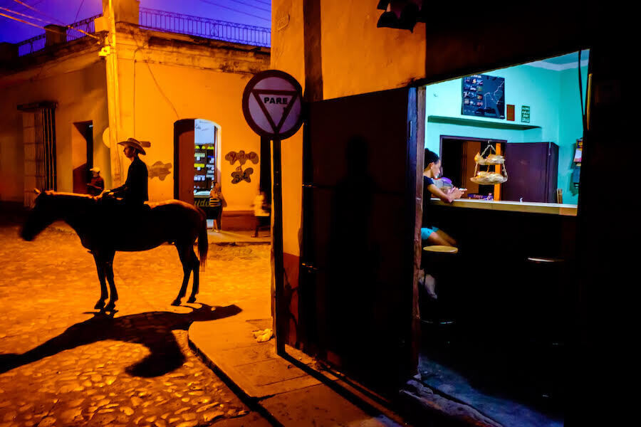 una escena callejera en México. Un hombre sobre un caballo y una chica en la barra de un bar
