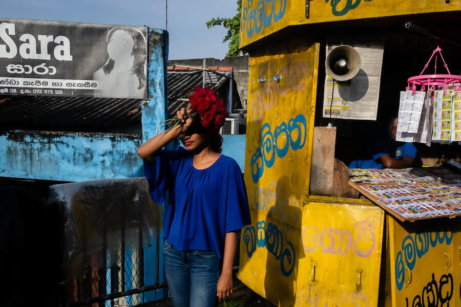 una chica mexicana protege sus ojos del sol con una mano en la que tiene un ramo de rosas rojas