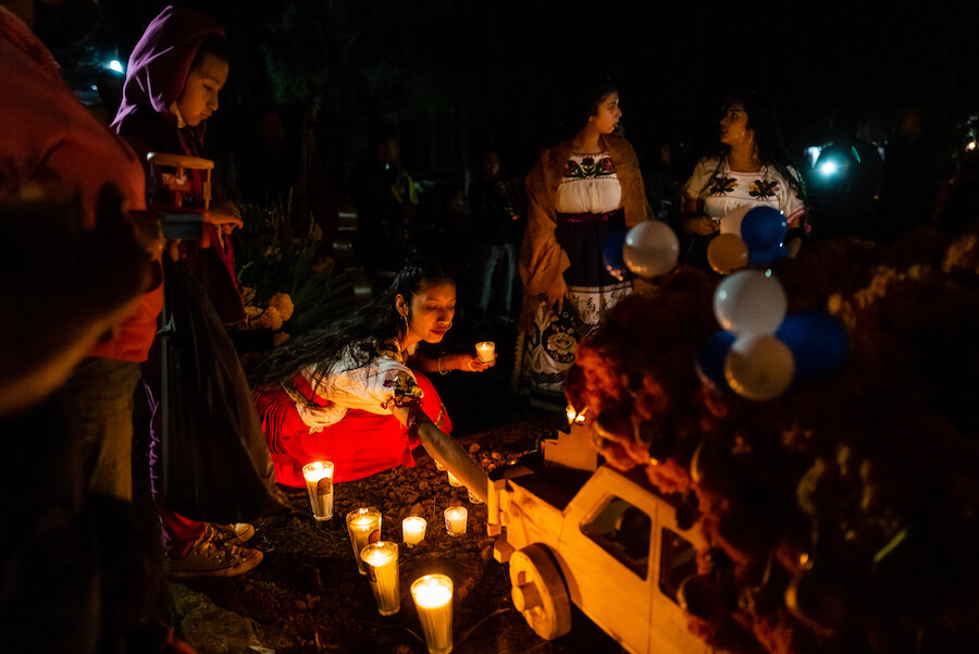 una chica enciende velas en el día de muertos en México