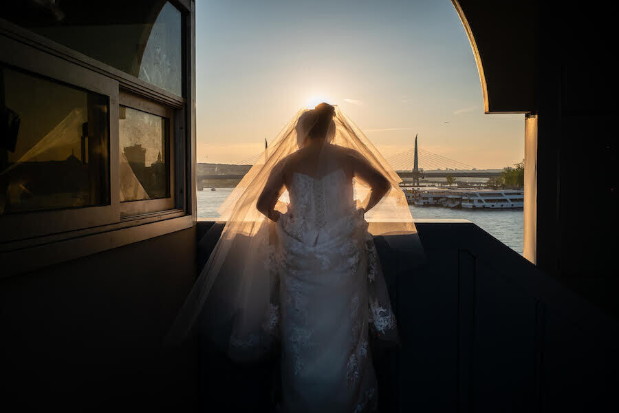 una chica vestida de novia se asoma a una ventana que da al mar