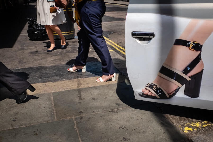la puerta de un coche con la fotografía del pie de una mujer se mezcla con el plano de varias personas a las que solo se les ven los pies