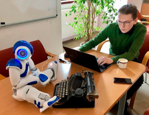 un científico con un ordenador y un robot en con una máquina de escribir