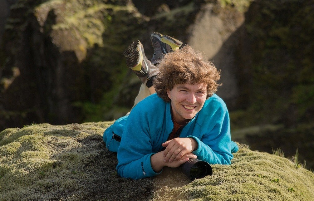 El fotógrafo Daniel Kordan tumbado sobre una roca en un paisaje lleno de musgo