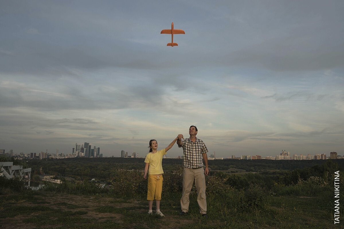 Padre e hija en un descampado ven una avioneta pasar