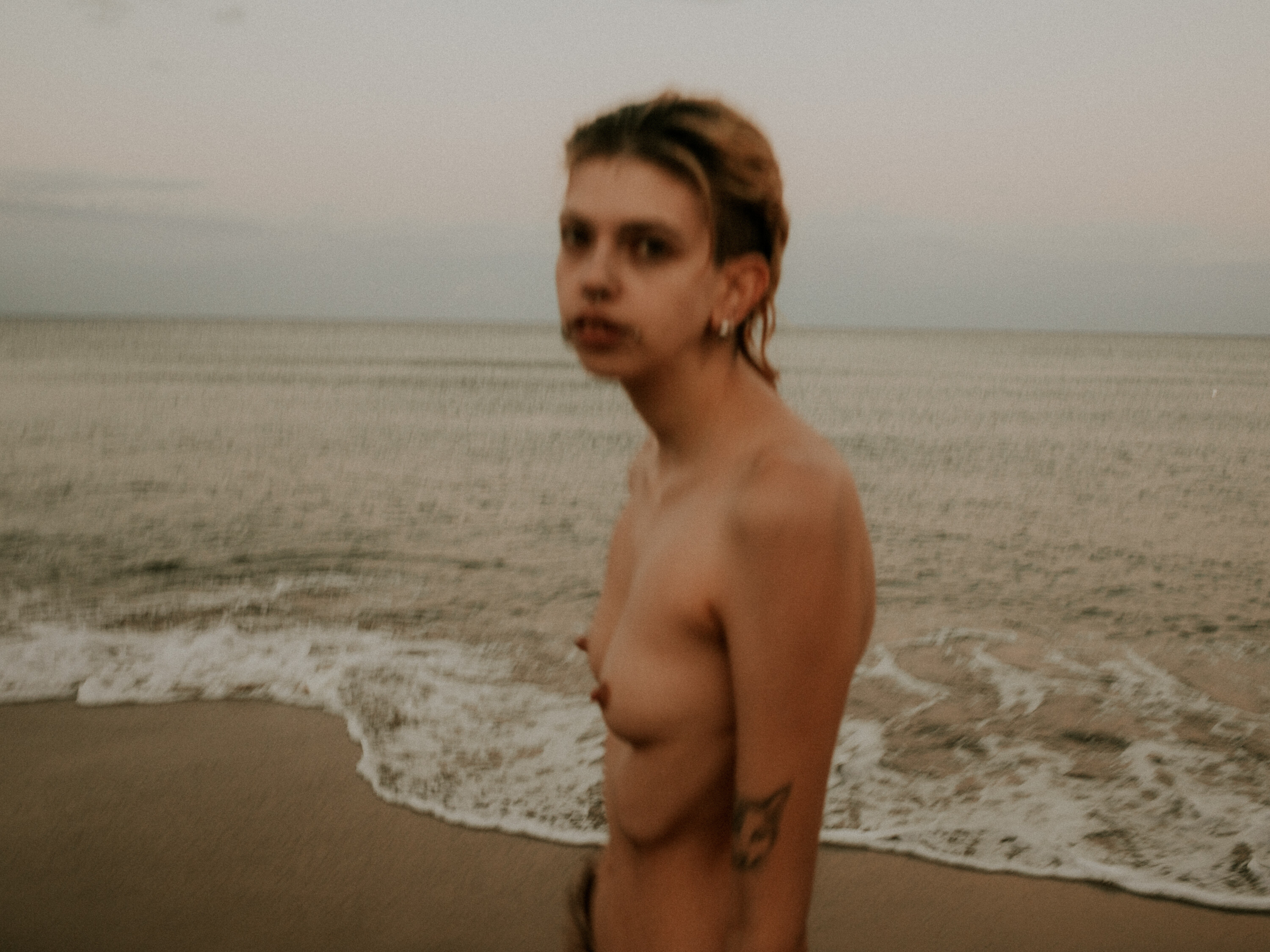 Una chica en la orilla de la playa desnuda.