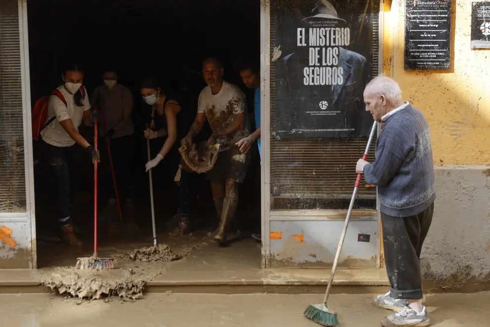 Un señor mayor y varios voluntarios quitando barrado de las calles en Valencia.