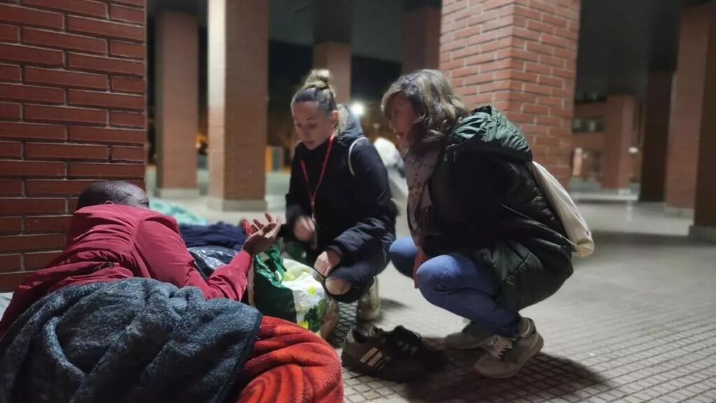 Dos chicas voluntarias ayudando a una persona durmiendo en la calle.