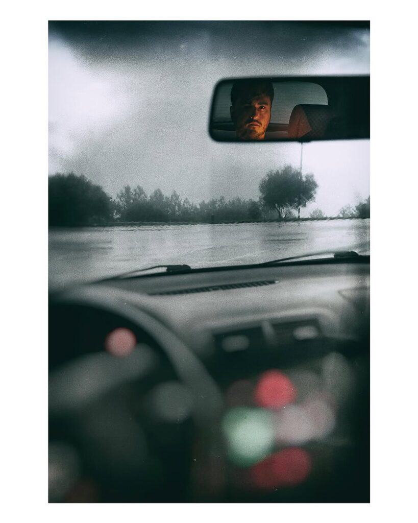 Una persona reflejada en el retrovisor interior de un coche.